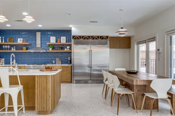 a dining hall with stainless steel appliances kitchen island a table and chairs