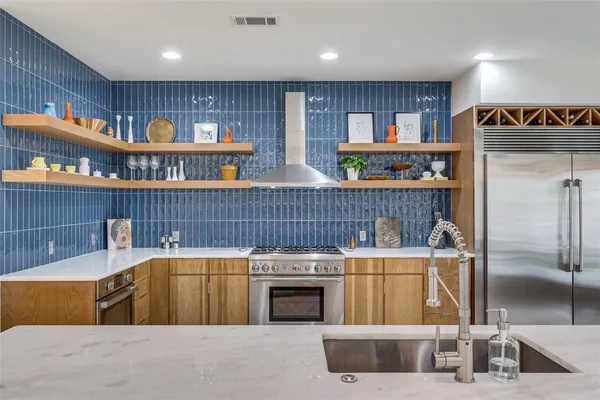 a kitchen with stainless steel appliances granite countertop a refrigerator a stove and a sink