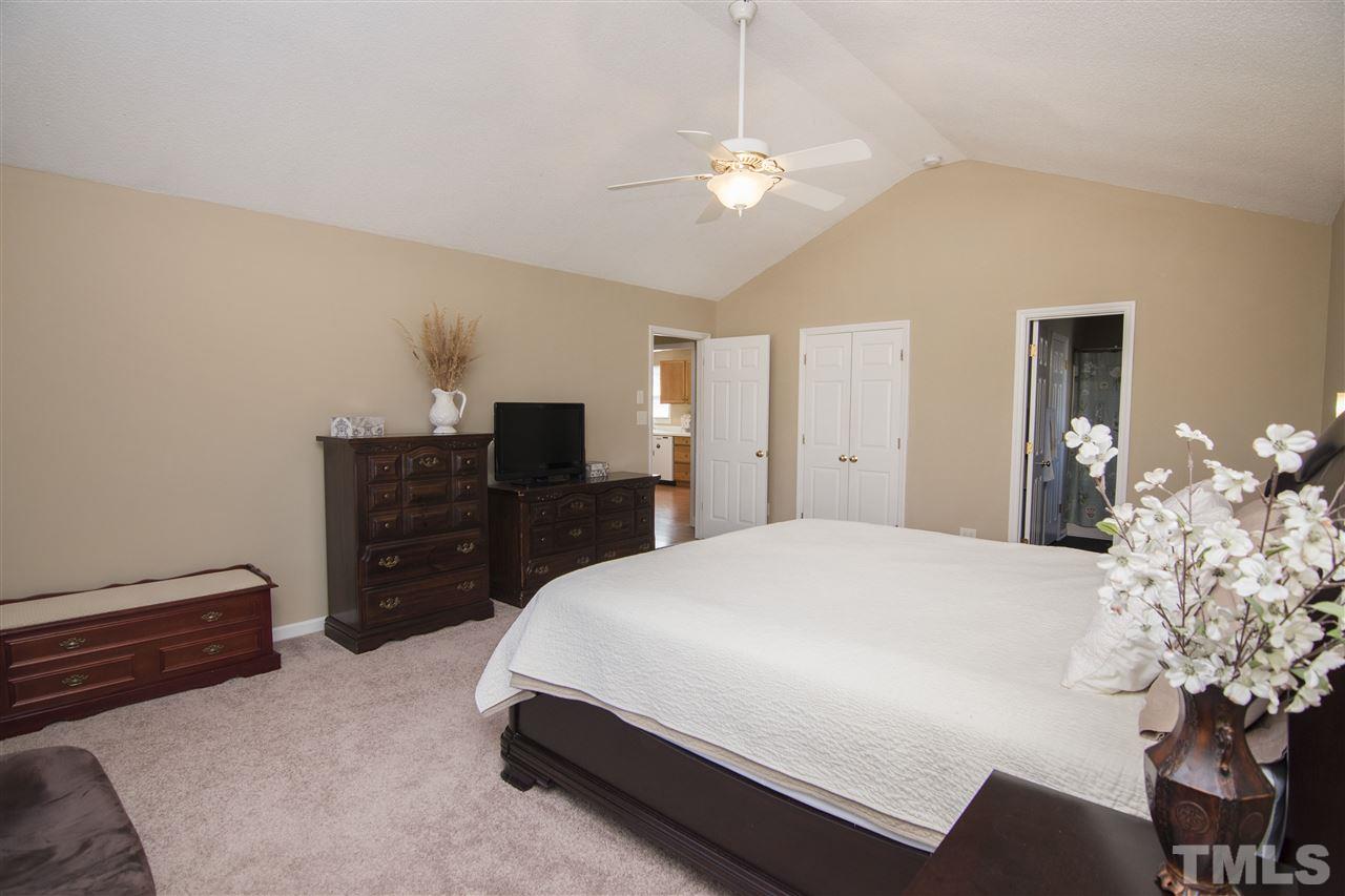 1849 Sanders Road Willow Spring, NC 27592 - Photo 17 of 25 a spacious bedroom with a bed and a chandelier