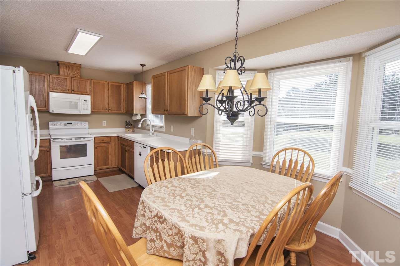 1849 Sanders Road Willow Spring, NC 27592 - Photo 8 of 25 a kitchen with stainless steel appliances granite countertop a stove a sink a microwave dining table and chairs