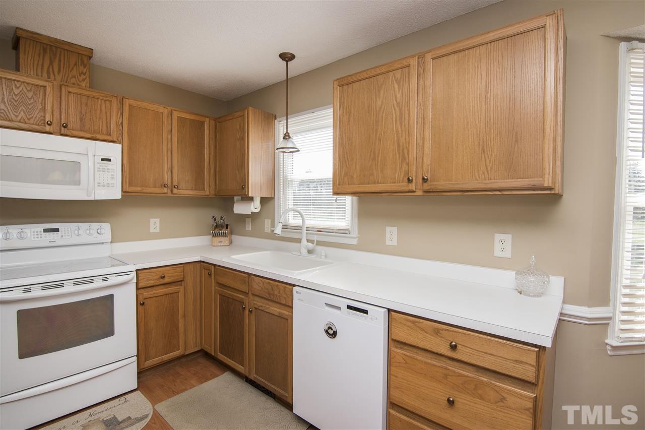 1849 Sanders Road Willow Spring, NC 27592 - Photo 9 of 25 a kitchen with white cabinets white stainless steel appliances and sink