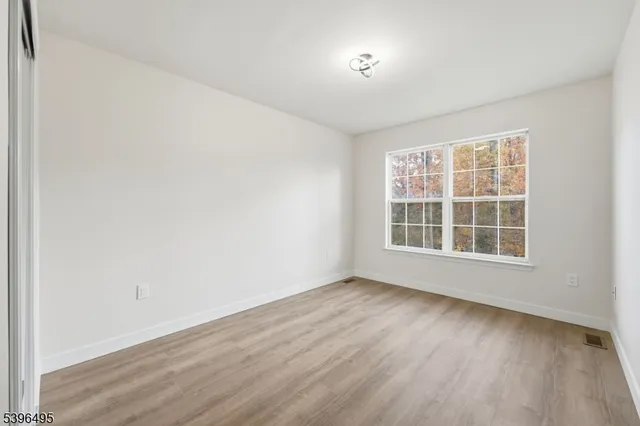 an empty room with wooden floor chandelier fan and windows