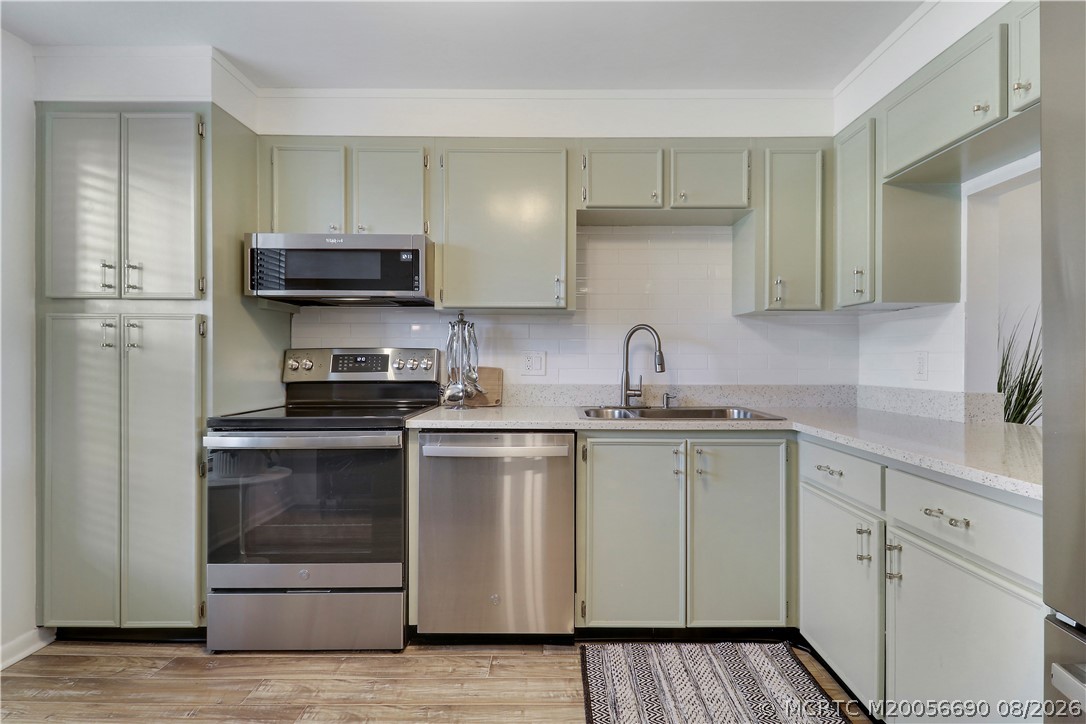 1862 Southwest Palm City Road, Unit 103 Stuart, FL 34994 - Photo 11 of 29 Tastefully updated kitchen featuring soft coastal cabinetry, quartz countertops and a classic subway tile backsplash. Stainless steel appliances and wood-look tile flooring complete this move-in ready space with a convenient pass-through to the living area.
