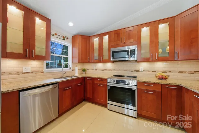a kitchen with stainless steel appliances granite countertop wooden cabinets a stove top oven a sink and dishwasher