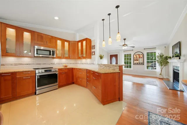 a kitchen with stainless steel appliances granite countertop a stove a sink dishwasher and a microwave oven with white cabinets