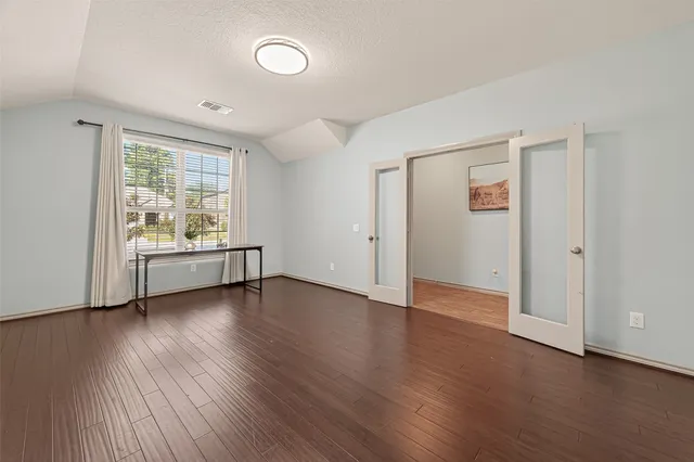 an empty room with wooden floor and windows