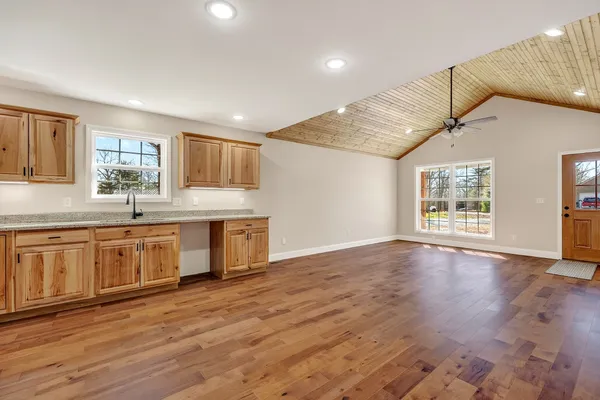 a open kitchen with granite countertop a stove a sink wooden floor cabinets and a dining table