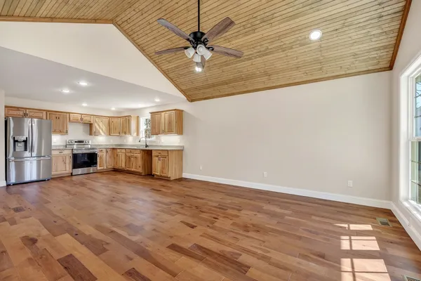 a view of an empty room with kitchen and a window