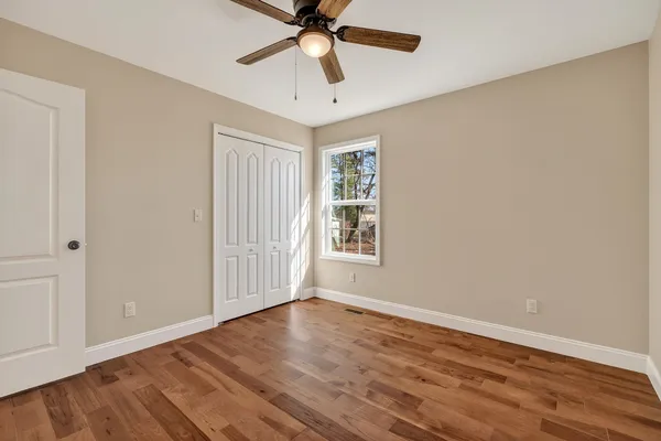 a view of an empty room with window and wooden floor
