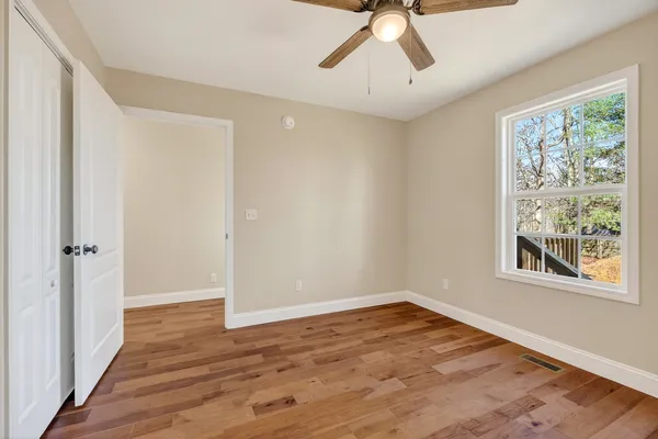 a view of empty room with wooden floor and fan