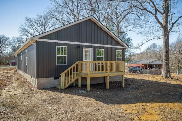 a view of a house with a yard chairs and wooden fence
