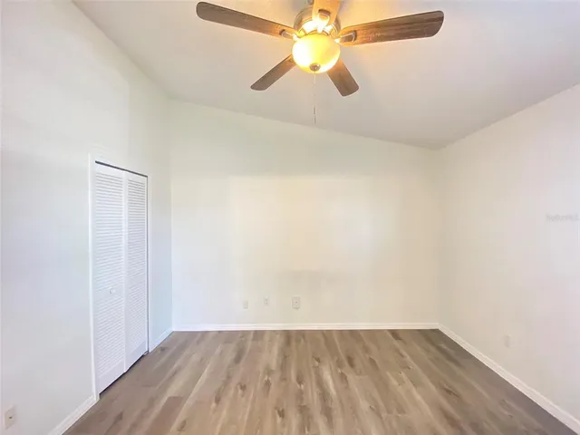 a view of an empty room with chandelier fan and a window