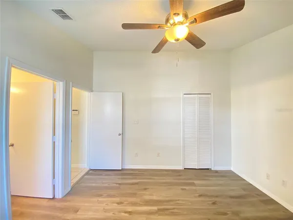 a view of an empty room and window with a ceiling fan