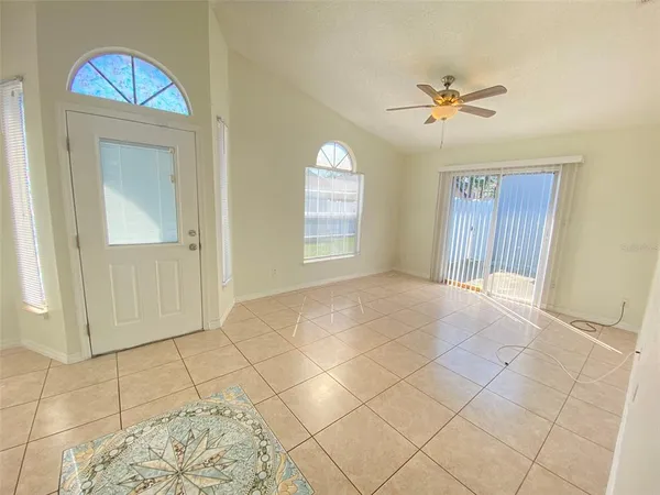 a view of an empty room with window and chandelier fan