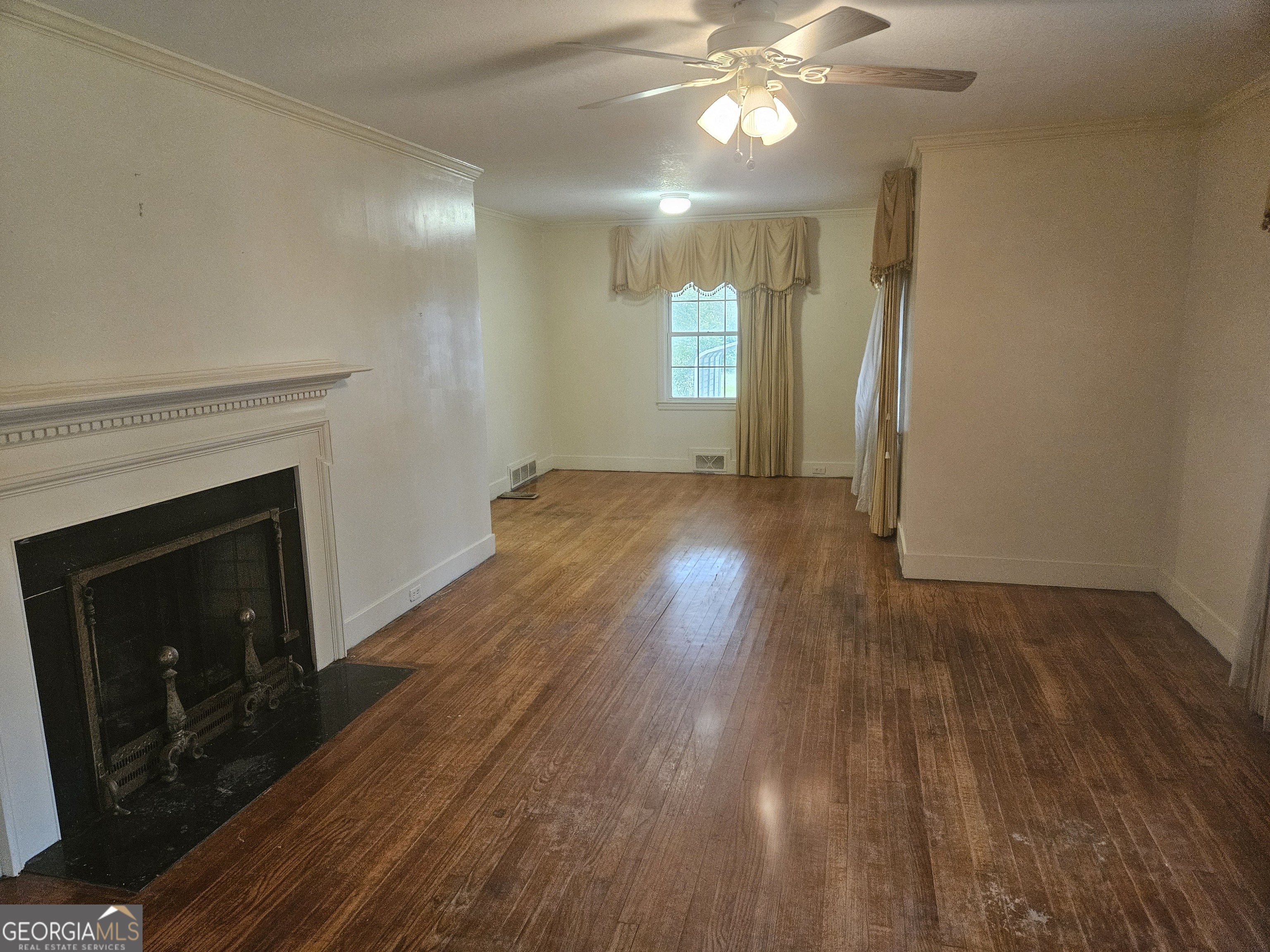 846 Harvey Street Millen, GA 30442 - Photo 9 of 34 an empty room with wooden floor fan and windows