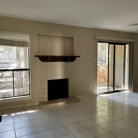 an empty room with windows and fireplace