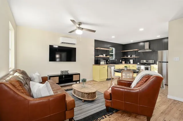 a living room with furniture kitchen and a flat screen tv