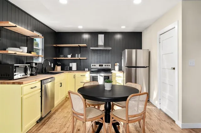 a kitchen with stainless steel appliances granite countertop a refrigerator a stove a sink a dining table and chairs