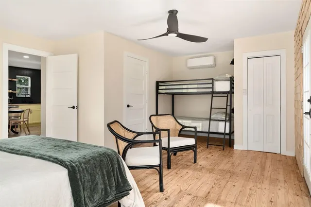 a bedroom with a bed a chair and potted plant on the dresser