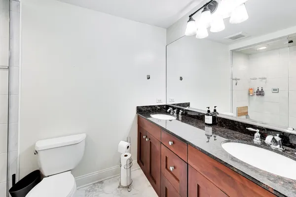 a bathroom with a granite countertop double vanity sink mirror and toilet