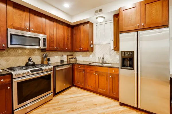 a kitchen with stainless steel appliances granite countertop a stove microwave refrigerator and sink