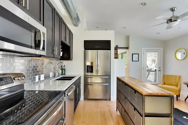 a kitchen with stainless steel appliances granite countertop a sink a stove and a refrigerator