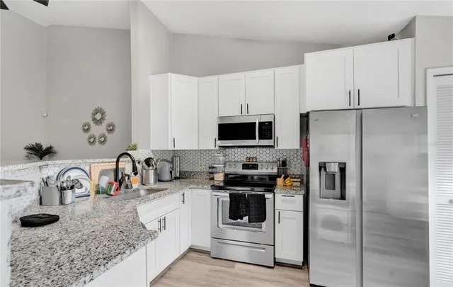 a kitchen with stainless steel appliances granite countertop a sink a stove a refrigerator and cabinets