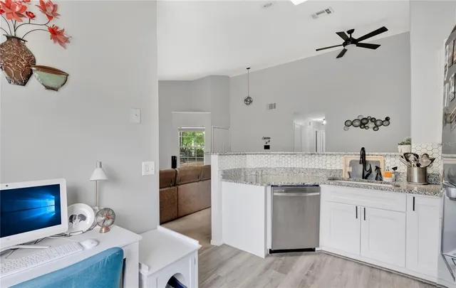 a kitchen with a sink dishwasher and white cabinets with wooden floor