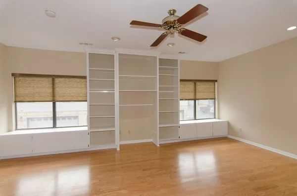 an empty room with cabinet and windows