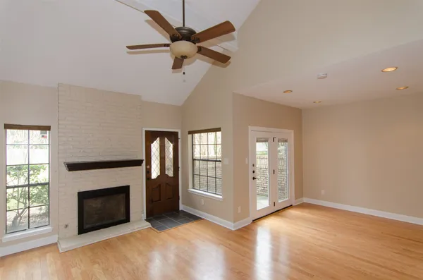 an empty room with windows fireplace and a kitchen view