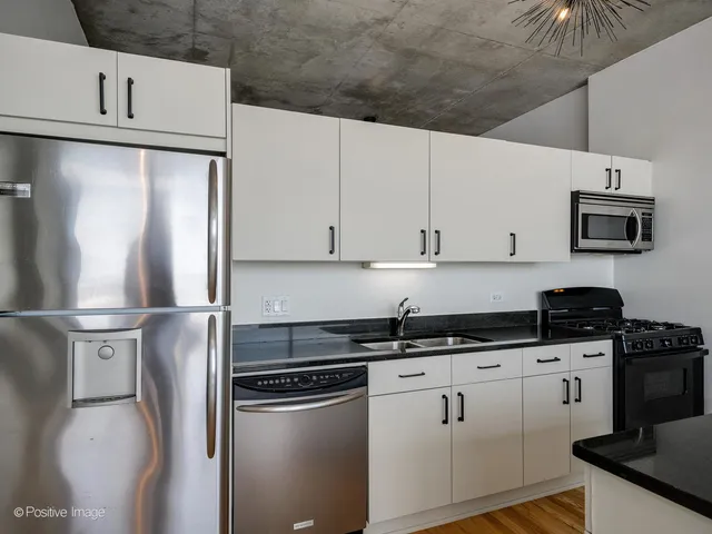 a kitchen with stainless steel appliances granite countertop a refrigerator sink and white cabinets