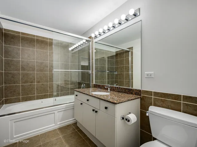 a bathroom with a granite countertop sink a toilet a mirror and shower