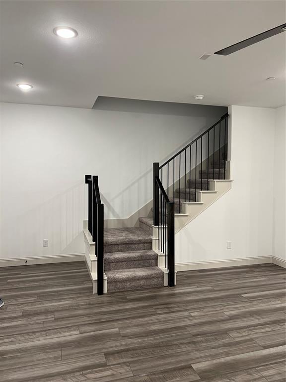 6041 Roper Road McKinney, TX 75070 - Photo 4 of 24 Staircase featuring dark carpet treads, white risers, and black metal balusters