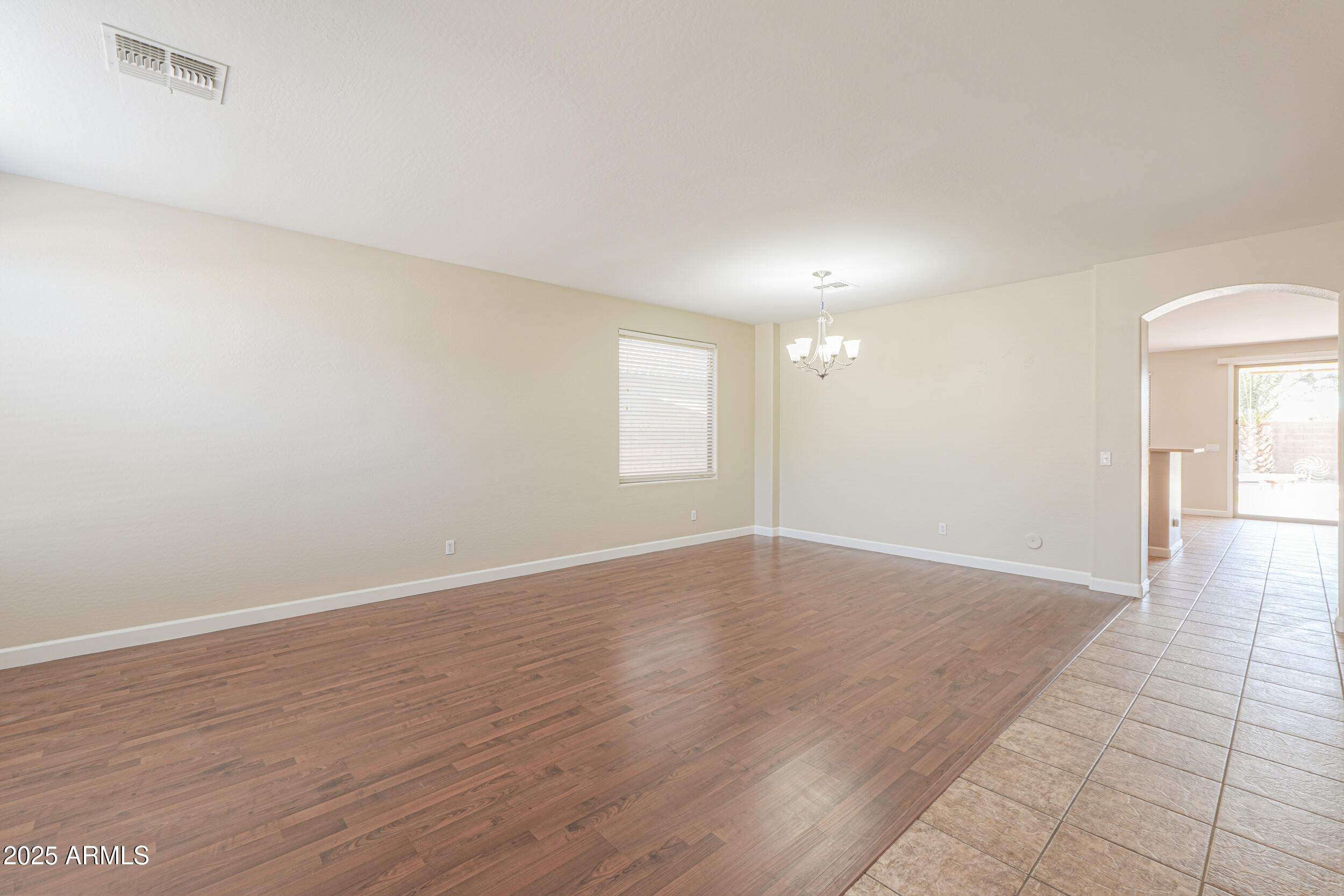 43223 West Venture Road Maricopa, AZ 85138 - Photo 10 of 70 a view of an empty room with wooden floor and a window