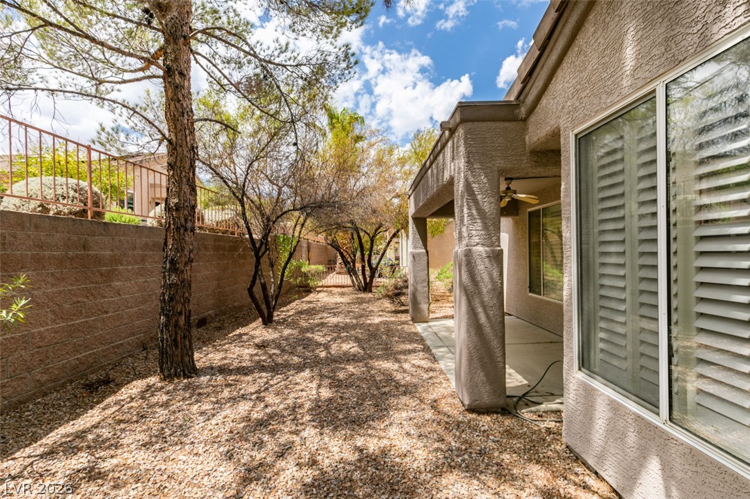 2189 Chapman Ranch Drive Henderson, NV 89012 - Photo 44 of 60 Mature trees shade a low-maintenance gravel yard bordering a covered concrete patio.