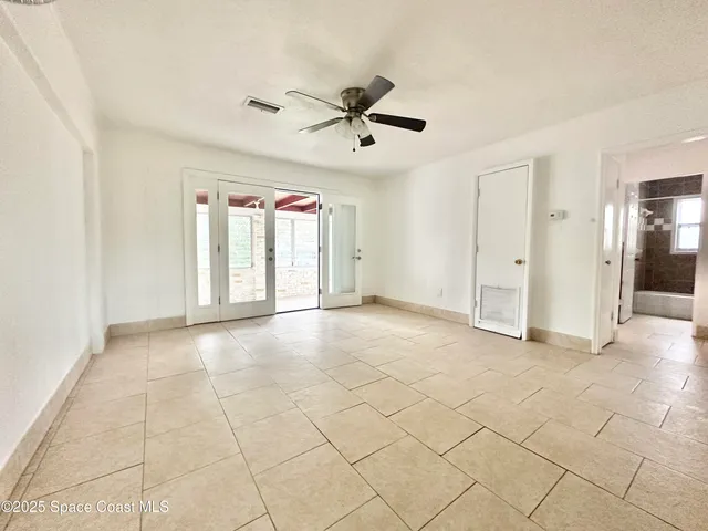 an empty room with windows and fan