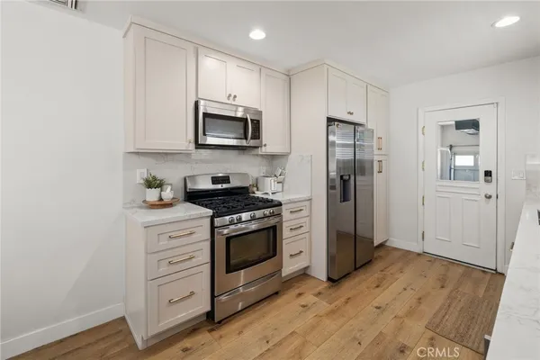 a kitchen with stainless steel appliances white cabinets and wooden floor