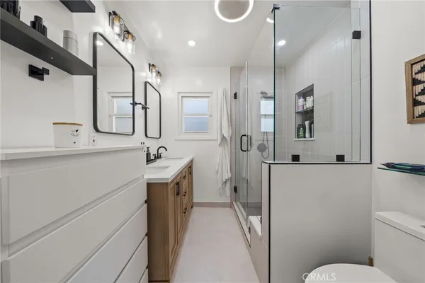 a bathroom with a sink a toilet a mirror and shower