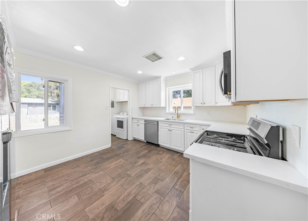 2074 Summit Avenue Pasadena, CA 91103 - Photo 12 of 23 a kitchen with white cabinets a sink a window and stainless steel appliances