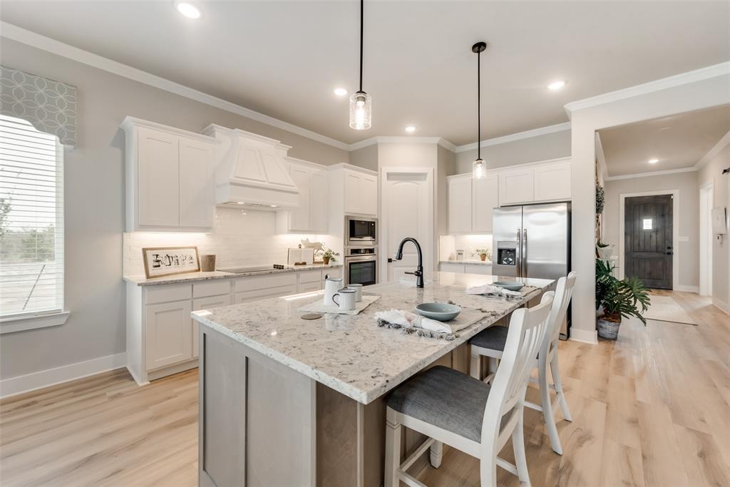 250 Brown Road Leonard, TX 75452 - Photo 13 of 29 Kitchen featuring a large central island with seating, white cabinetry, integrated stainless steel appliances, wood-finish flooring, and pendant lighting