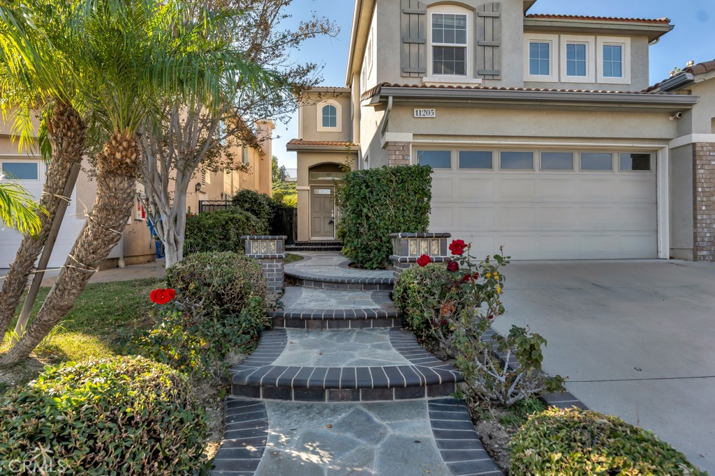 11205 Salerno Porter Ranch Porter Ranch, CA 91326 - Photo 2 of 43 a front view of a house with a yard and a garden