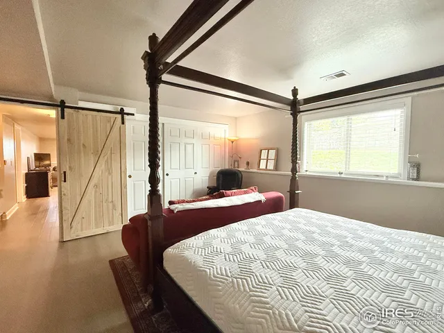a bedroom with a bed window and wooden floor