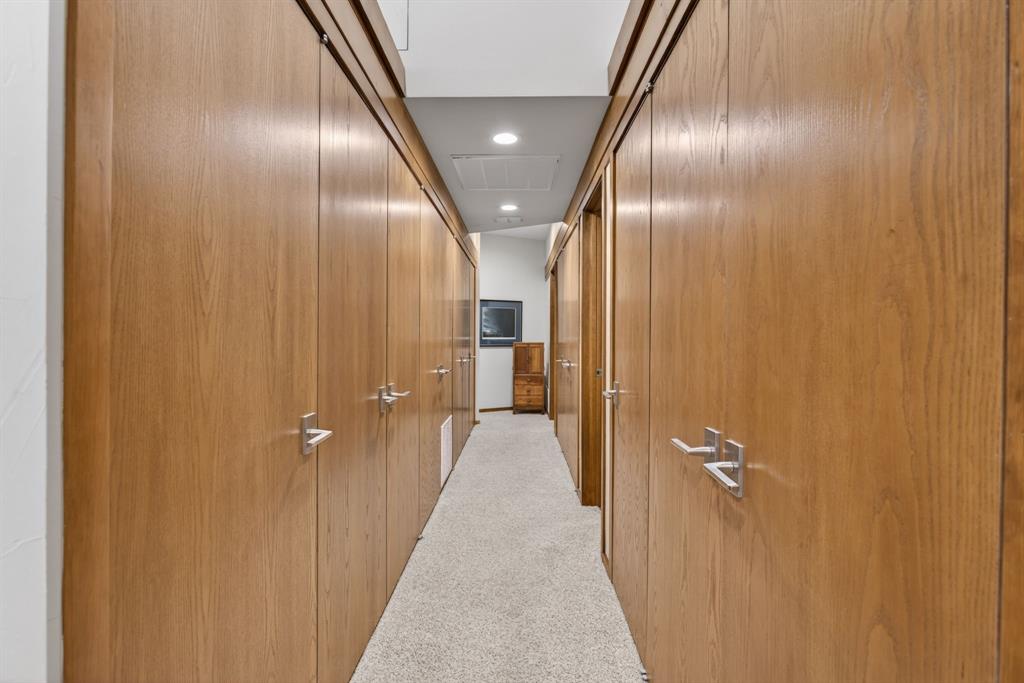 1080 North Greenbrier Road Nocona, TX 76255 - Photo 18 of 40 Hallway featuring extensive wood-finish cabinetry with brushed nickel hardware, recessed ceiling lighting, and light-toned carpet flooring