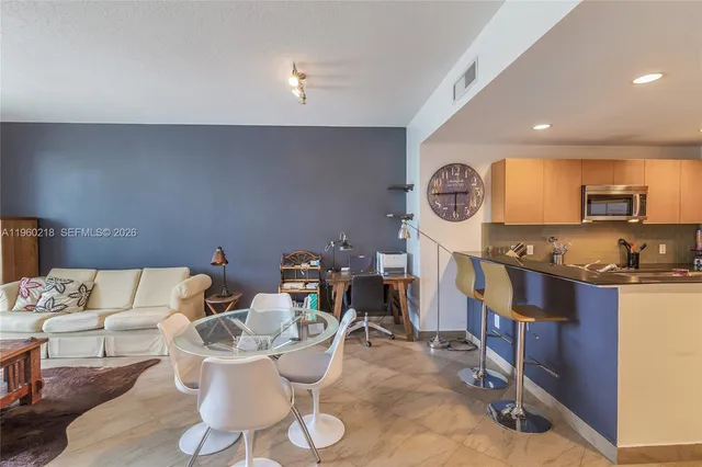 a living room with furniture a clock and a view of kitchen