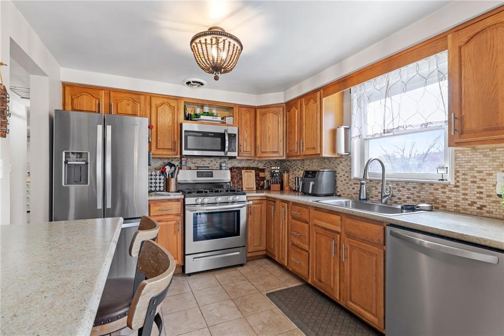 1075 Fiddleback Drive McKees Rocks, PA 15136 - Photo 12 of 34 a kitchen with stainless steel appliances granite countertop a sink a stove a refrigerator cabinets and a dining table with wooden floor