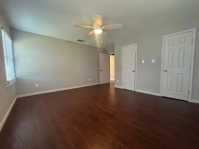 an empty room with wooden floor and windows