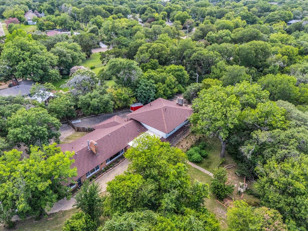 421 Rice Avenue Waco, TX 76708 - Photo 12 of 22 Expansive property with a brown shingle roof and a concrete driveway, set amidst abundant mature trees