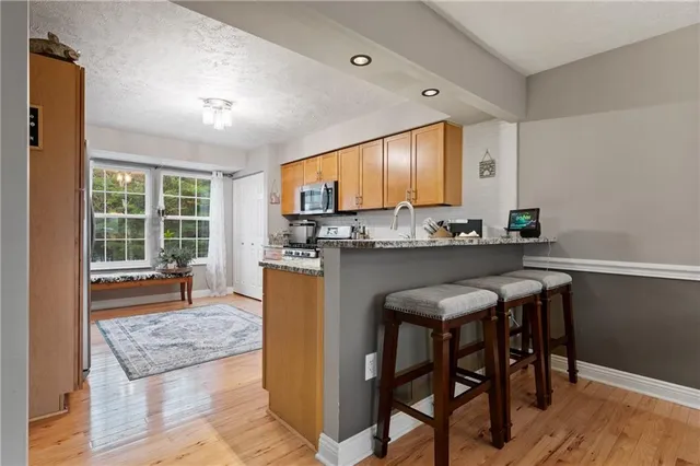 a kitchen with stainless steel appliances granite countertop a table chairs sink and cabinets