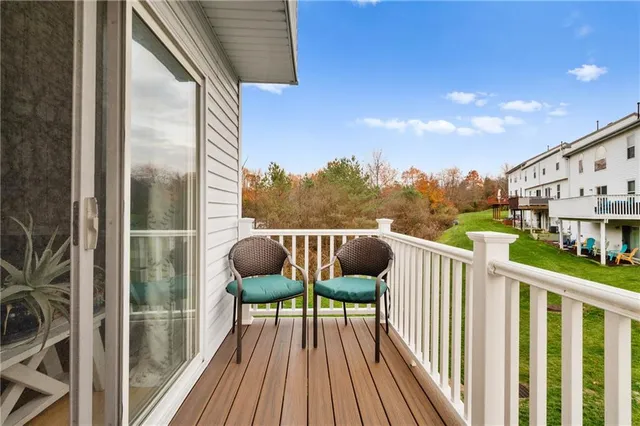 a balcony with wooden floor outdoor seating and yard in the back