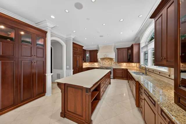 a large kitchen with a large counter top a sink stainless steel appliances and cabinets